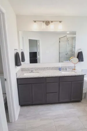 a bathroom with a granite countertop double vanity sink and mirror