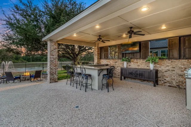 a view of a patio with table and chairs under an umbrella with a barbeque
