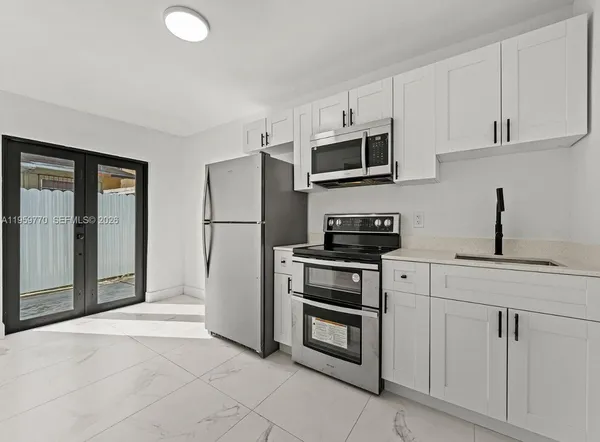 a kitchen with stainless steel appliances granite countertop a refrigerator a stove a microwave and white cabinets