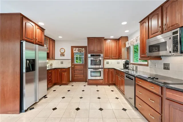 a kitchen with stainless steel appliances granite countertop a refrigerator and a stove top oven