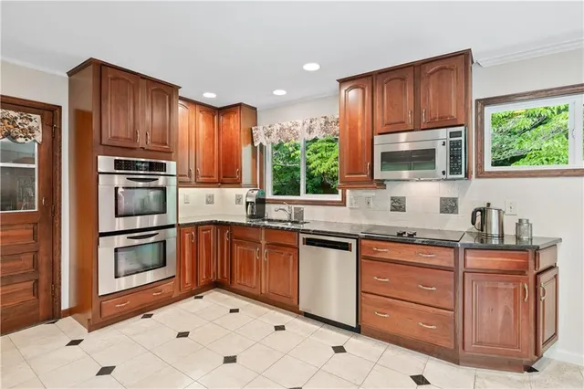 a kitchen with granite countertop wooden cabinets a stove a oven and a window