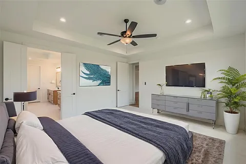 a bedroom with a bed a potted plant and a flat screen tv