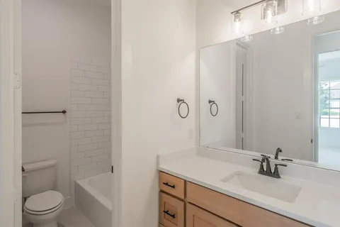 a bathroom with a granite countertop sink toilet a mirror and shower