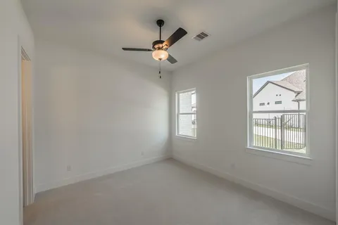 an empty room with windows and ceiling fan