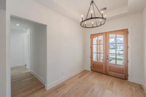 an empty room with wooden floor mirror and windows