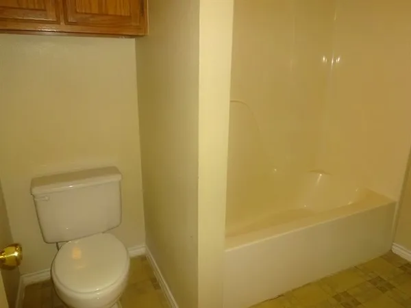 a white toilet sitting next to a white wall