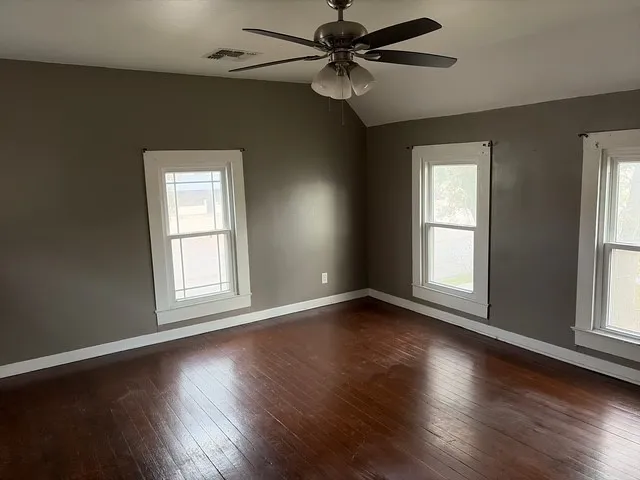 a view of an empty room with wooden floor and a window