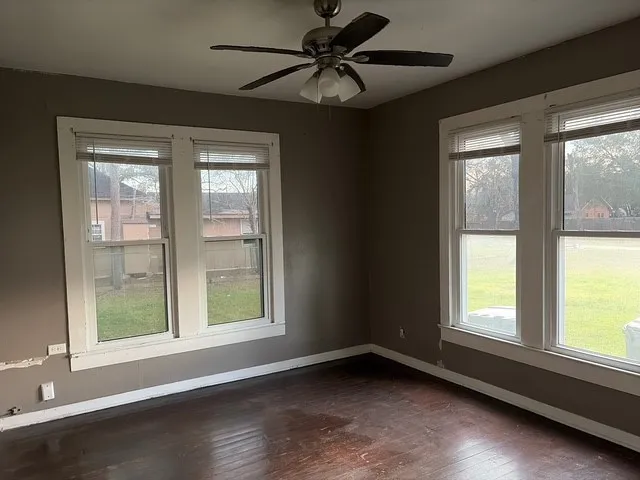 a view of an empty room with a window and wooden floor