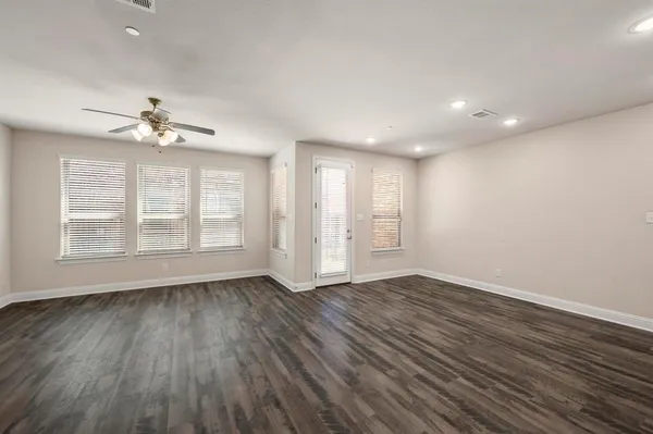 a view of an empty room with a window and wooden floor