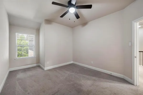 an empty room with a window and a fan