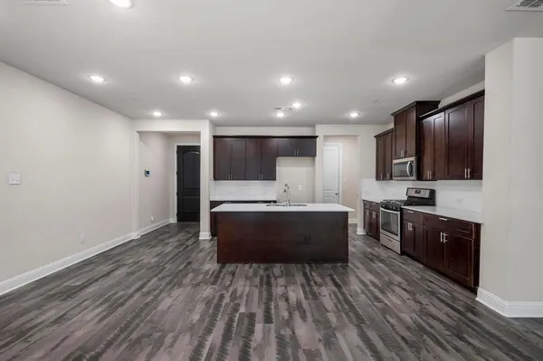 a large white kitchen with stainless steel appliances granite countertop a stove a sink dishwasher a microwave oven and a refrigerator with wooden floor