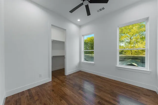 a view of an empty room with a window and wooden floor