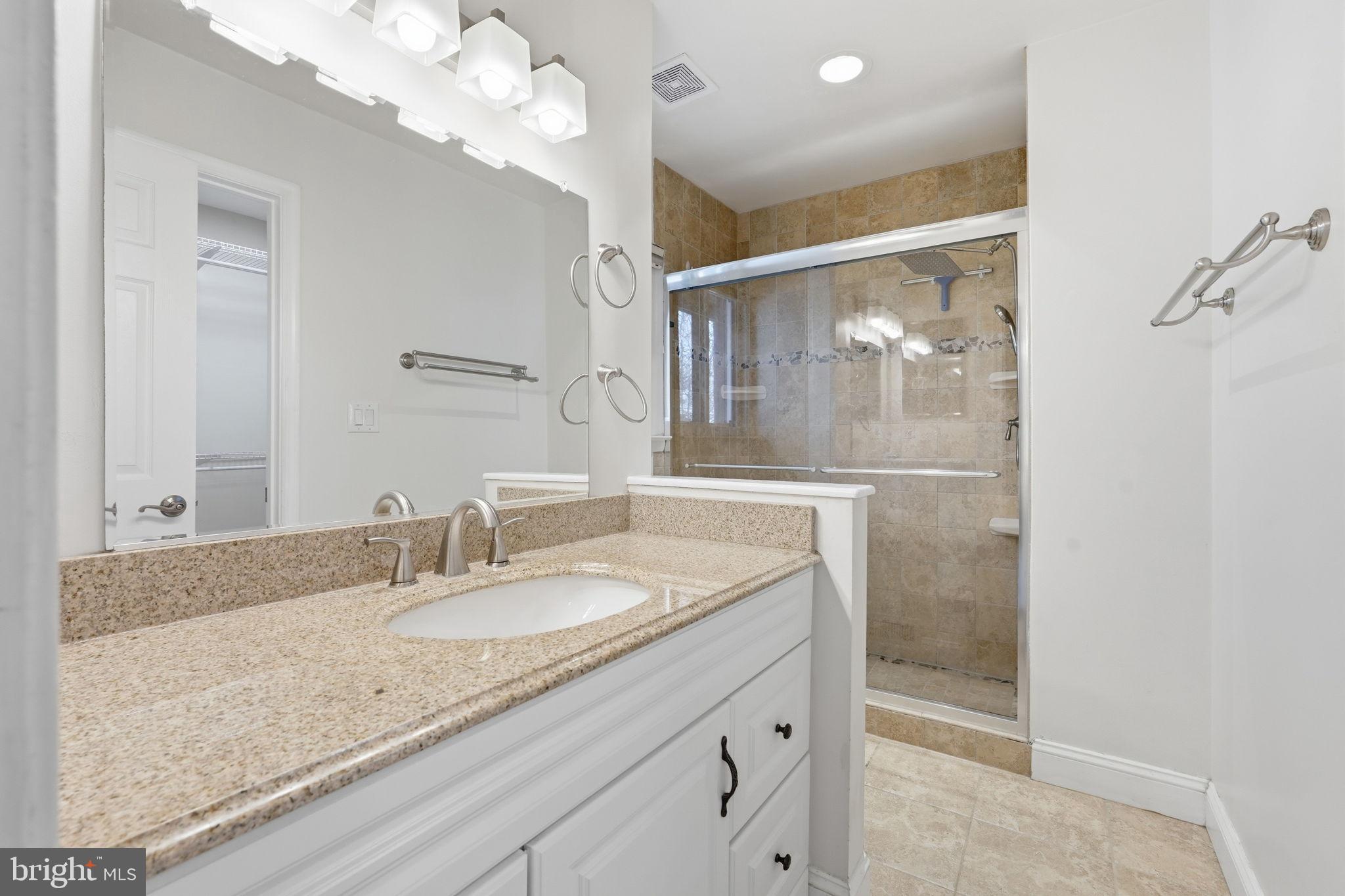 1942 Winterport Cl Reston, VA 20191 - Photo 12 of 19 a bathroom with a granite countertop sink a mirror and a shower