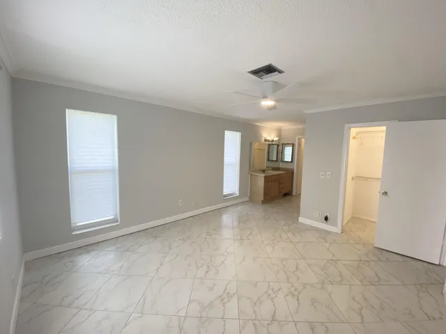 an empty room with a ceiling fan and windows