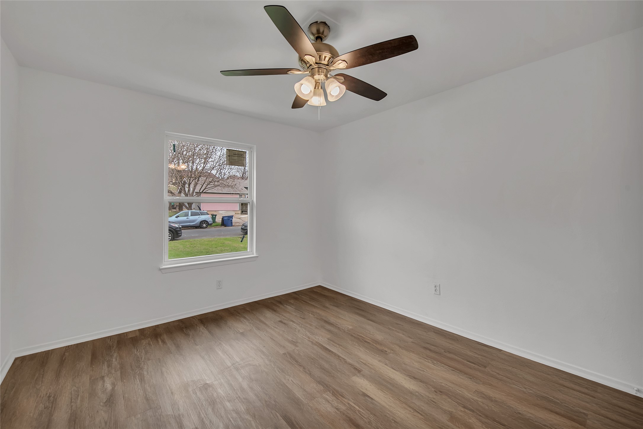 7209 Gunnison Pass Austin, TX 78724 - Photo 13 of 19 A well-lit bedroom with durable wood-look flooring and a functional ceiling fan.