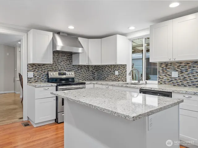 a kitchen with stainless steel appliances granite countertop a sink stove and cabinets