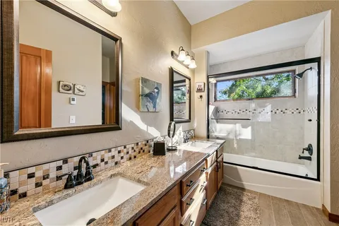 a bathroom with a granite countertop sink a mirror and shower