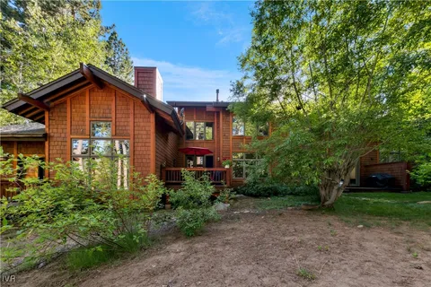 a view of a house with a small yard plants and large tree