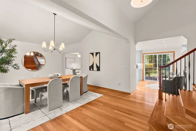 a dining room with wooden floor a chandelier a potted plant and windows