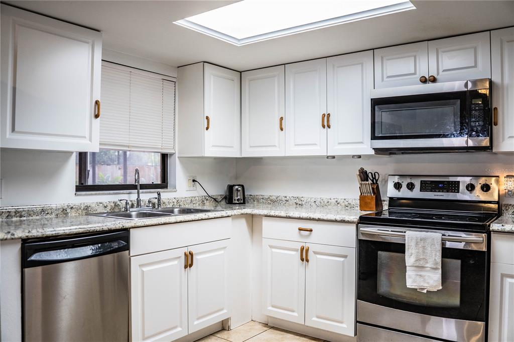 207 24th Court Southwest Winter Haven, FL 33880 - Photo 19 of 75 a kitchen with granite countertop a stove sink and microwave