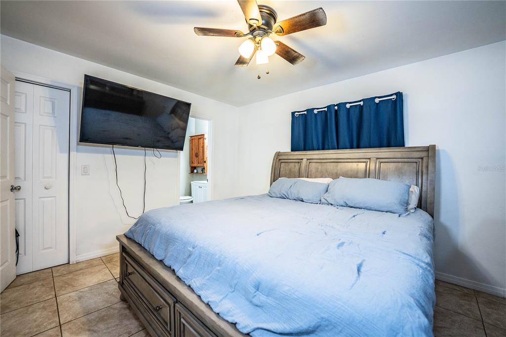 207 24th Court Southwest Winter Haven, FL 33880 - Photo 25 of 75 a bedroom with a bed a flat screen tv and a chandelier