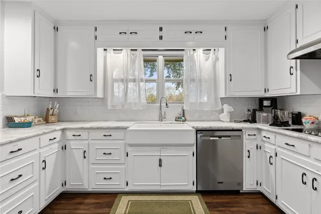 a kitchen with granite countertop white cabinets white stainless steel appliances with a sink and dishwasher
