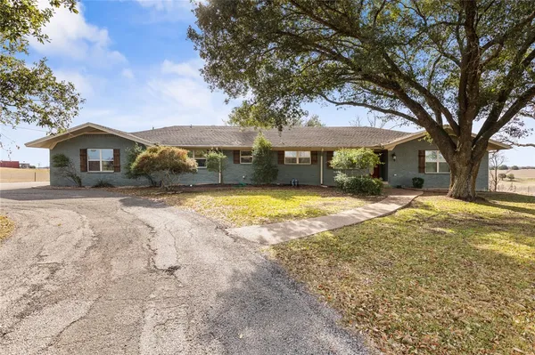 a view of a house with a big yard and large tree