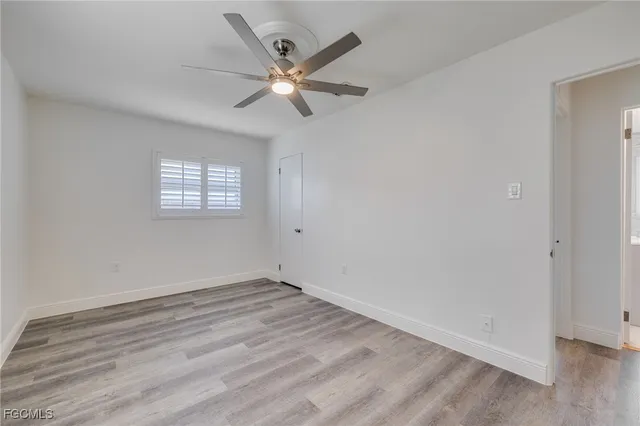 an empty room with wooden floor fan and windows