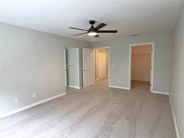 an empty room with ceiling fan and window