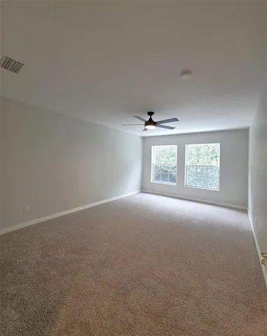 a view of a big room with windows and chandelier fan