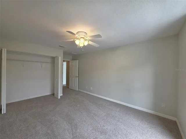 an empty room with a chandelier fan and a window