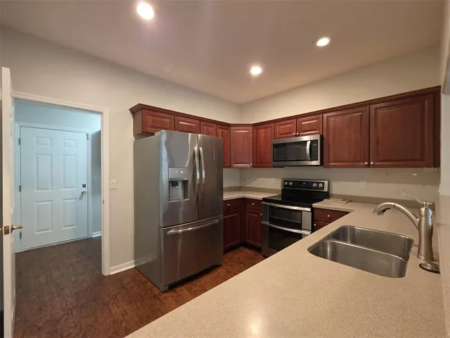 a kitchen with stainless steel appliances granite countertop a refrigerator a stove top oven a sink and dishwasher