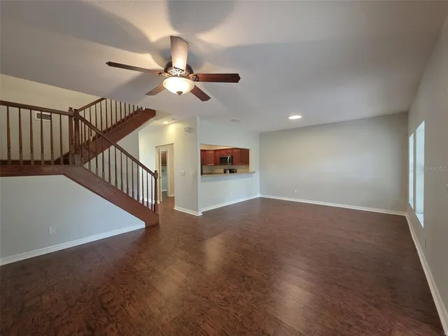a view of a hallway with a ceiling fan and wooden floor