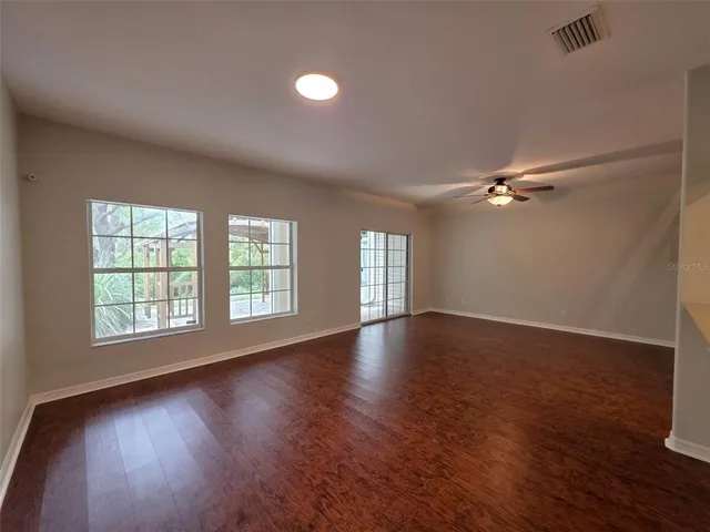 an empty room with wooden floor and windows