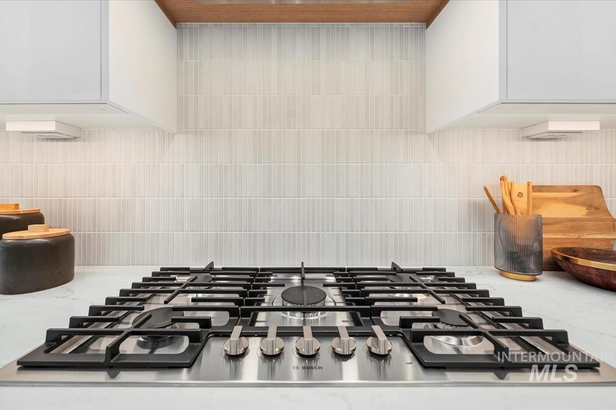6248 West Elmer Street Boise, ID 83703 - Photo 29 of 40 Kitchen view of stainless steel gas stovetop, white cabinetry, light stone counters, and tasteful backsplash