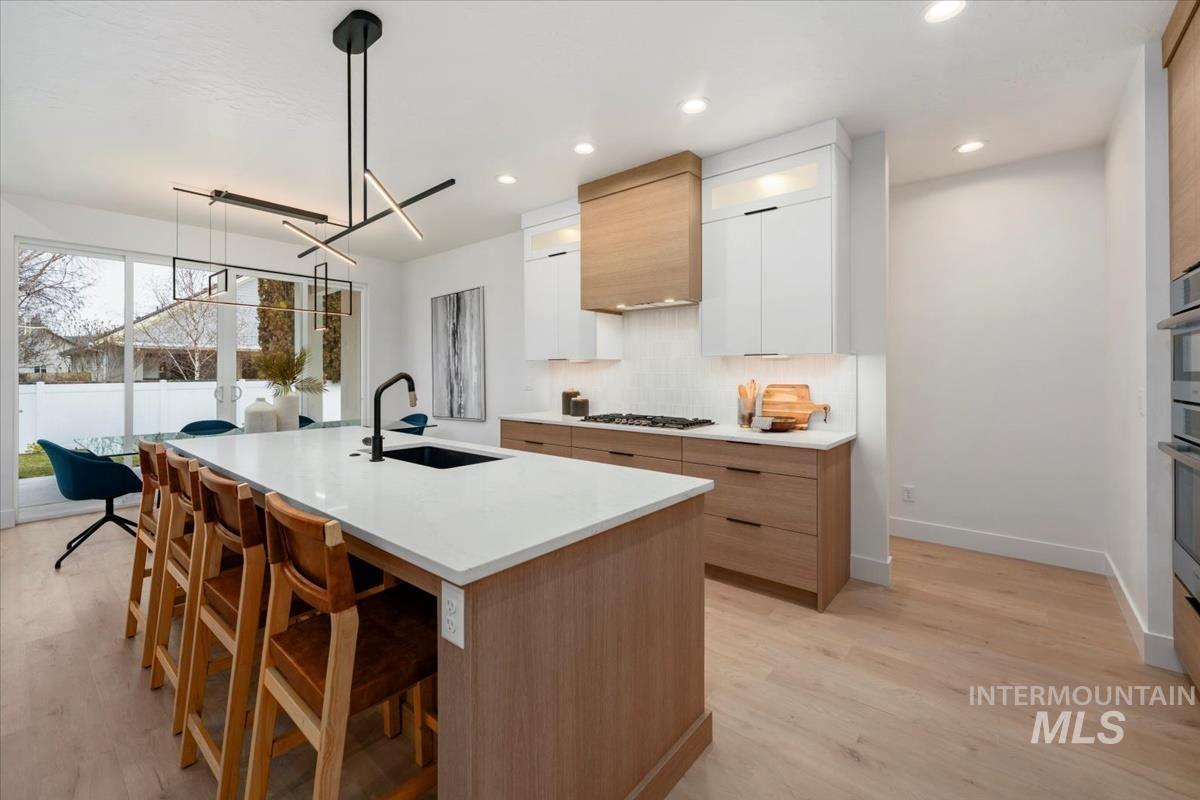 6248 West Elmer Street Boise, ID 83703 - Photo 32 of 40 Kitchen featuring a kitchen bar, decorative light fixtures, modern cabinets, light wood finished floors, and white cabinetry
