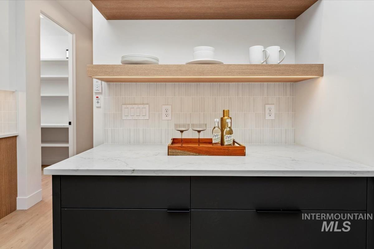 6248 West Elmer Street Boise, ID 83703 - Photo 34 of 40 Kitchen with dark cabinetry, open shelves, light stone counters, and decorative backsplash