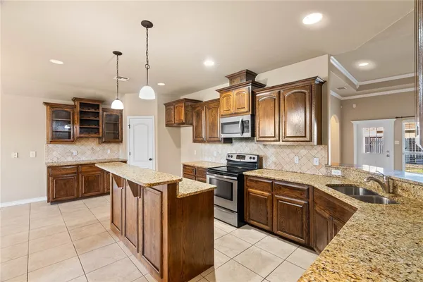 a kitchen with stainless steel appliances granite countertop a sink a stove top oven a counter space and cabinets