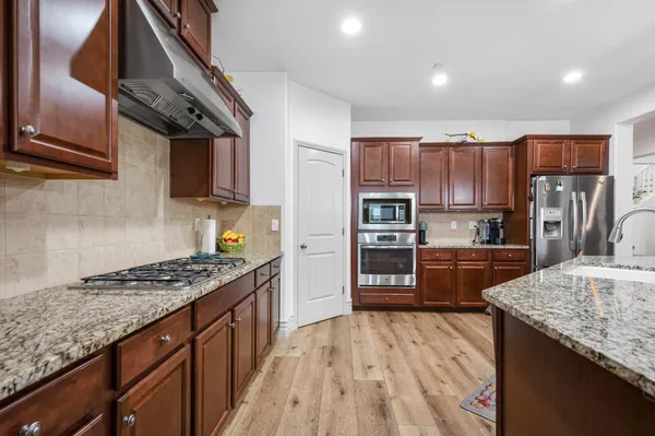 a kitchen with stainless steel appliances granite countertop a refrigerator a sink and a stove