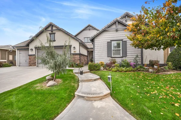 a front view of a house with a yard and potted plants