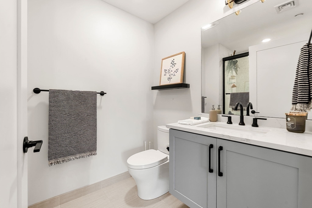 287 Maverick Street, Unit 201 Boston, MA 02128 - Photo 12 of 17 a bathroom with a toilet sink and mirror