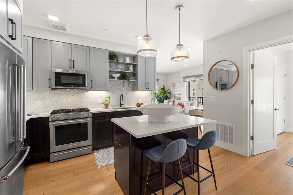 287 Maverick Street, Unit 201 Boston, MA 02128 - Photo 3 of 17 a kitchen with kitchen island granite countertop a sink a stove a refrigerator and island