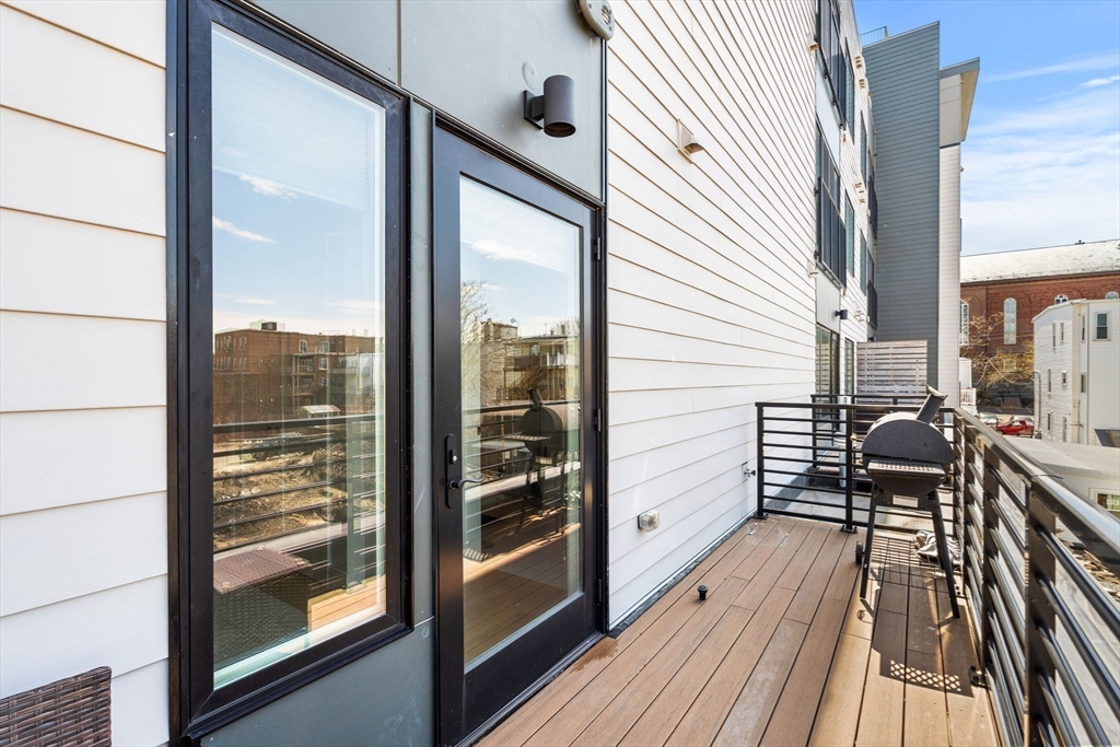 287 Maverick Street, Unit 201 Boston, MA 02128 - Photo 6 of 17 a balcony with wooden floor table and chairs