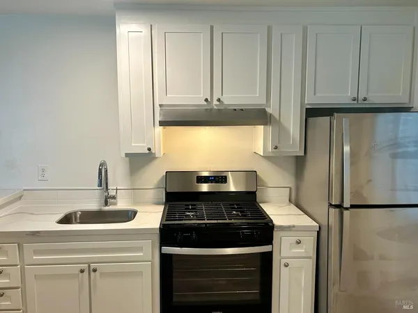 a kitchen with granite countertop a sink stove and cabinets
