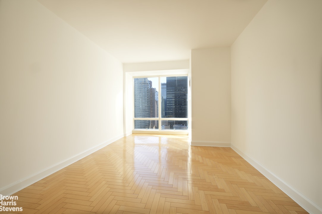 845 United Nations Plaza, Unit 33D Manhattan, NY 10017 - Photo 10 of 11 a view of an empty room with wooden floor and a window