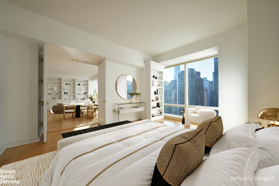 845 United Nations Plaza, Unit 33D Manhattan, NY 10017 - Photo 2 of 11 a bedroom with a bed a large mirror and furniture