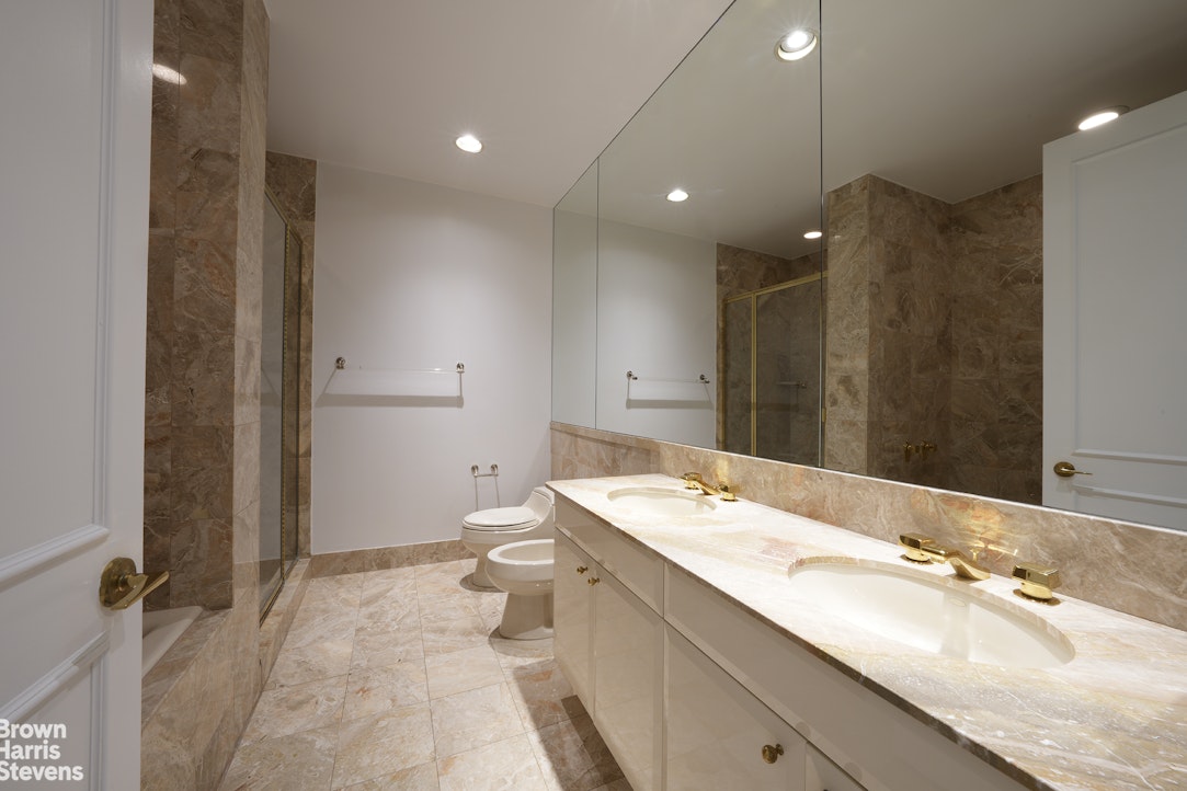 845 United Nations Plaza, Unit 33D Manhattan, NY 10017 - Photo 6 of 11 a bathroom with a double vanity sink mirror and toilet