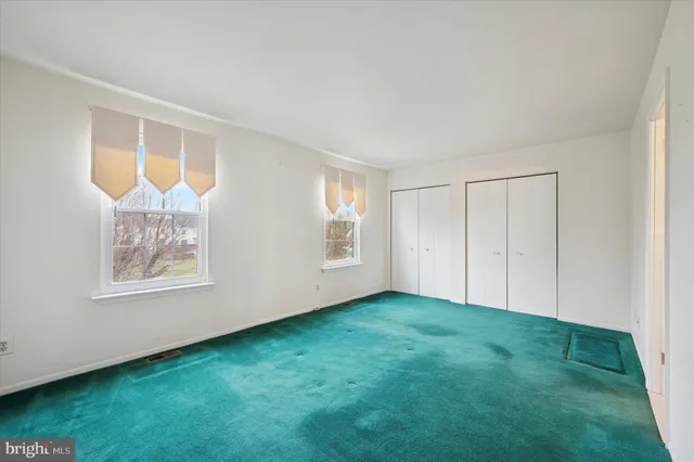 a view of an empty room with window and closet area