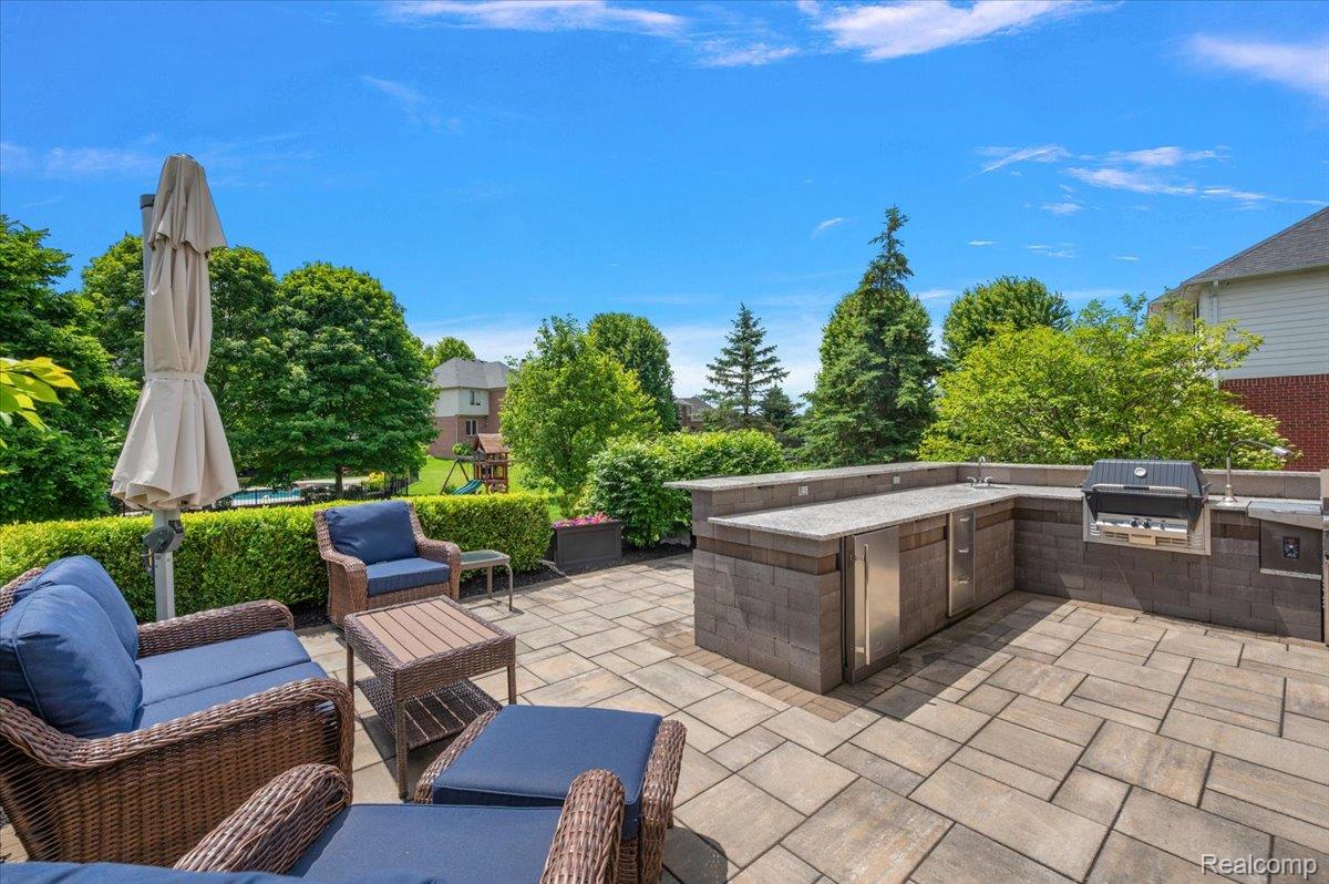 1422 Galena Rochester, MI 48306 - Photo 67 of 73 Spacious paver patio featuring a built-in outdoor kitchen with grill, stainless steel appliances, and ample counter space, surrounded by lush landscaping and mature trees