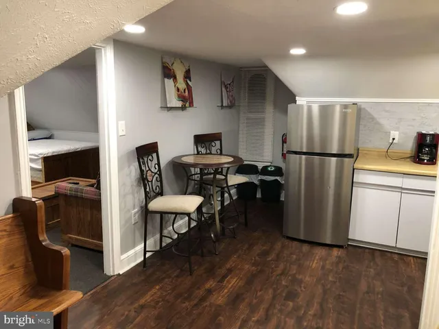 a kitchen with a refrigerator a stove a sink and a dining table with wooden floor